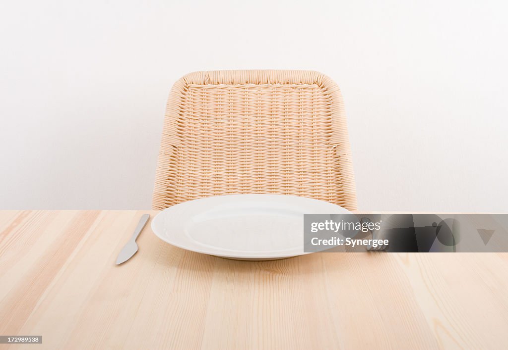 Image of a single plate with an empty seat at a table