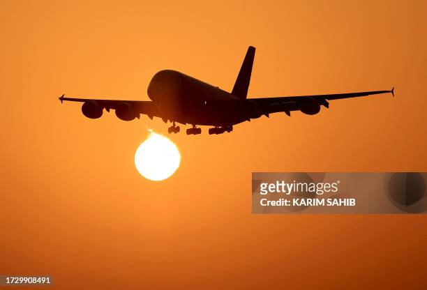 An Emirates Airlines plane lands at Dubai International Airport at sunrise in Dubai on October 17, 2023.