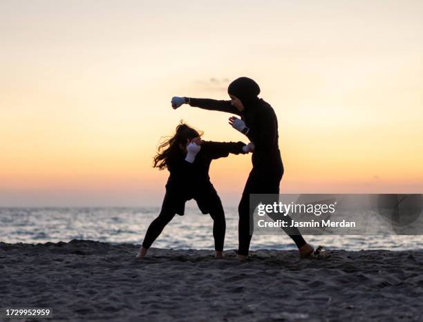 two female boxers having sparring on sunset beach - boxer stock pictures, royalty-free photos & images