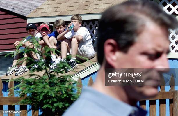 Vice President and Democratic presidential candidate Al Gore holds an impromptu press conference while neighborhood kids watch over a back yard fence...