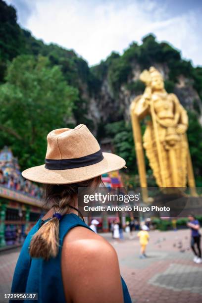 young woman wearing a hat admiring the batu caves in malaysia. - thaipusam stock pictures, royalty-free photos & images