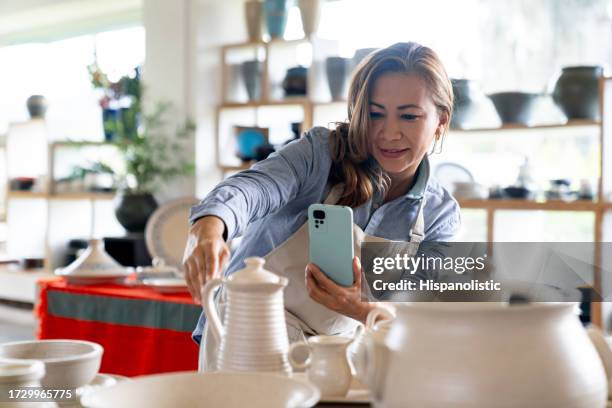 empresaria tomando fotos de sus productos en una tienda de cerámica - estudio de mercado fotografías e imágenes de stock