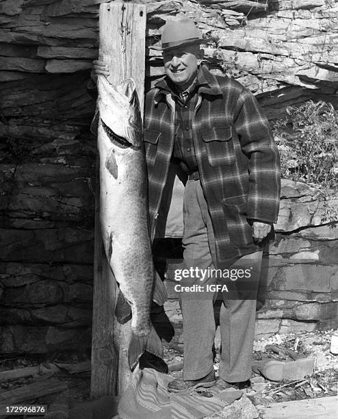 Man poses next to his 43 pound muskellunge caught on the Saint Lawrence River near Clayton, New York on October 26, 1952.