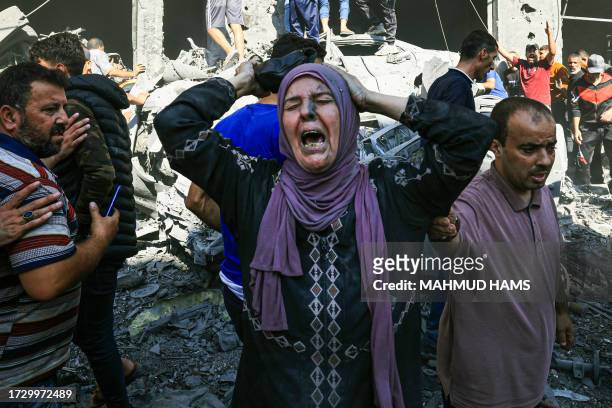 Graphic content / A Palestinian woman reacts as others rush to look for victims in the rubble of a building following an Israeli strike in Khan Yunis...