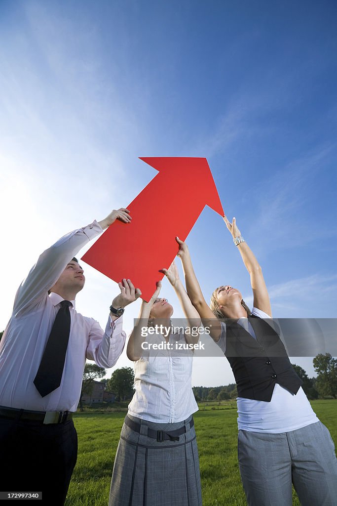 Three people holding red arrow