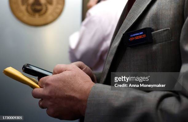 Rep. Thomas Massie wears a national debt clock button as he leaves a House Republican caucus meeting where the conference voted on a Speaker of House...