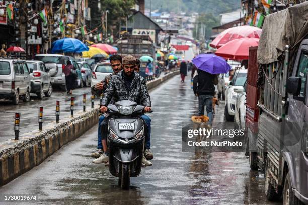 People walk during rainfall in Baramulla Jammu and Kashmir India on 17 October 2023.