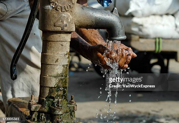 cleansing hands by way of metal water pump  - hygiene stockfoto's en -beelden
