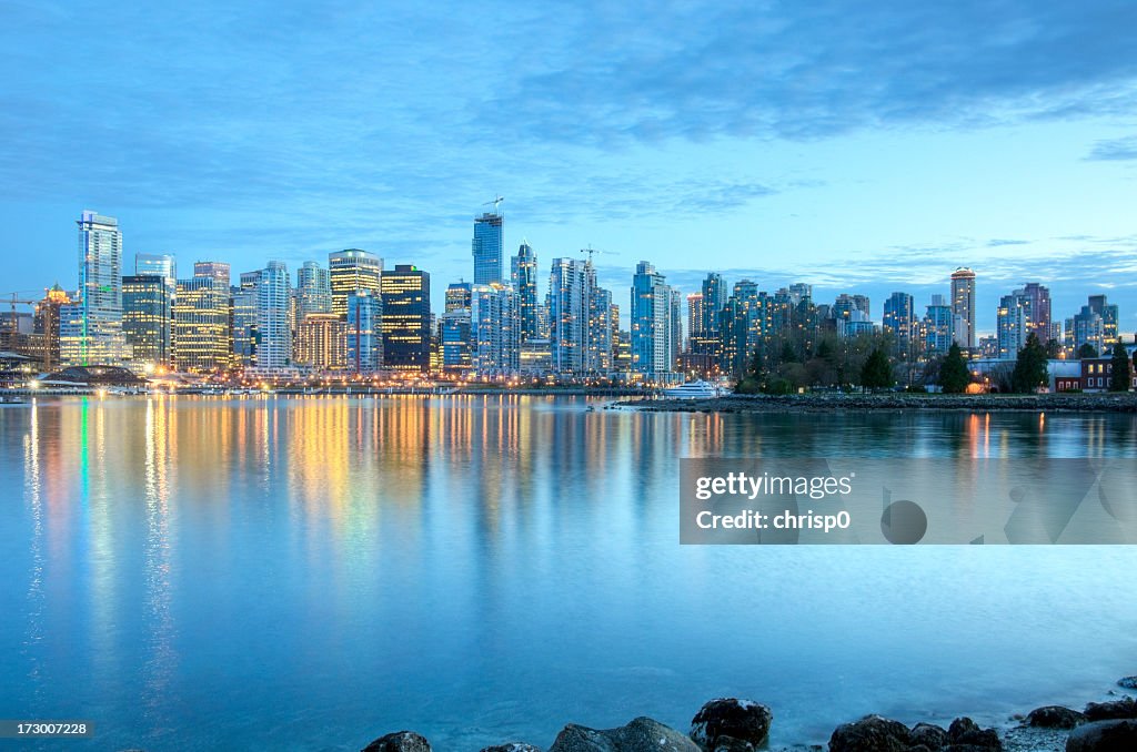 Illuminated Vancouver skyline at dusk as seen from the river