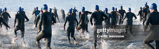 triathlon swimmers running into ocean - triathlon swim stock pictures, royalty-free photos & images