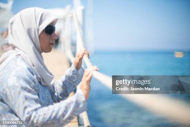 muslim woman enjoying on beach pier - hijab feet stockfoto's en -beelden