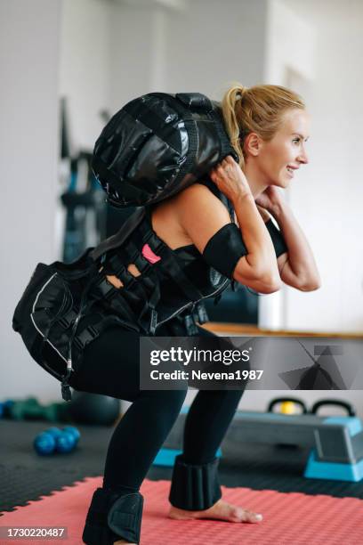 woman doing exercises in electrical muscular stimulation suit - ems stockfoto's en -beelden