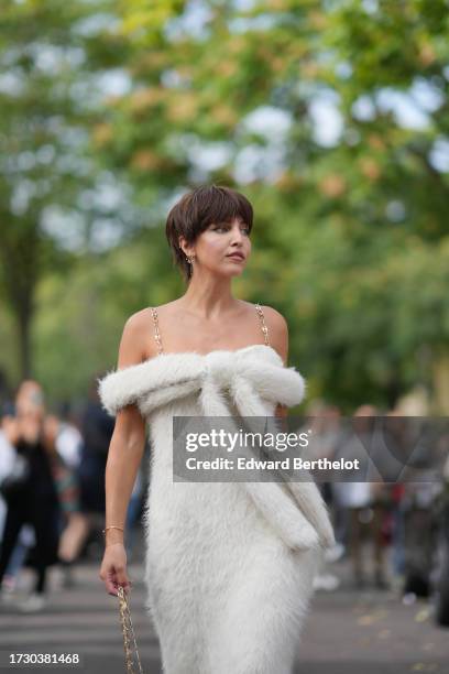 Carla Ginola wears a white fluffy faux fur off-shoulder dress, a golden metallic Rabanne bag, outside Rabanne, during the Womenswear Spring/Summer...