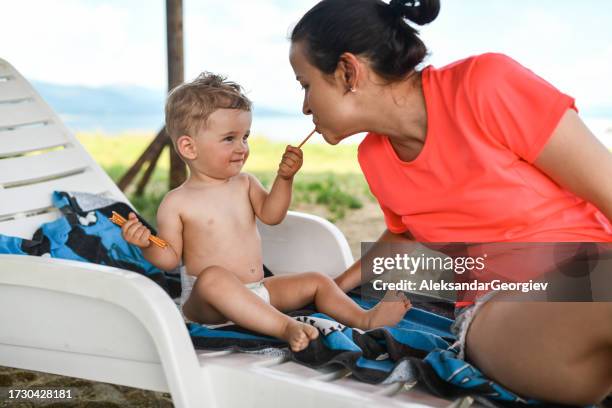 bambino ragazzo giocare alimentazione madre spuntini in spiaggia - baby eating toy foto e immagini stock