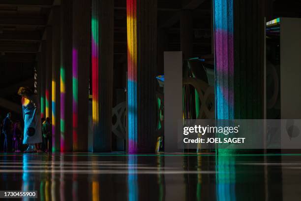 Visitors stroll along the columns of "Allegro, ma non troppo", a work by French visual artist Daniel Buren, enlightened in colours by the sun shining...