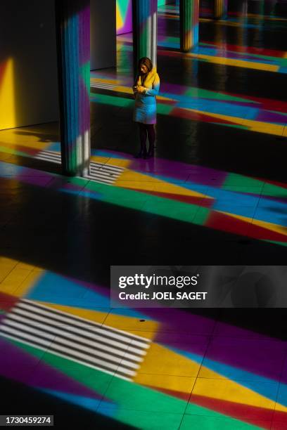 Visitor uses her smartphone next to the columns of "Allegro, ma non troppo", a work by French visual artist Daniel Buren, enlightened in colours by...