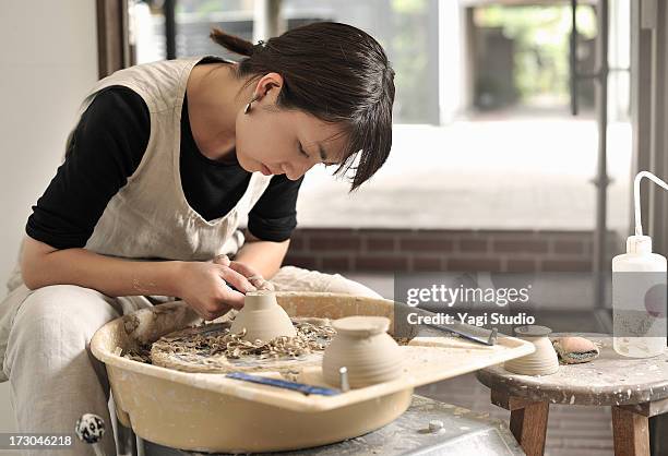 female potter are making a bowl in the studio - cerámica fotografías e imágenes de stock