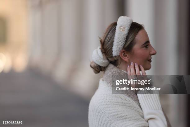 Stefanie Helen is seen wearing a fluffy white headband from Miu Miu, a creme-white knitted knee-length cape from Loro Piana, a light brown/beige...