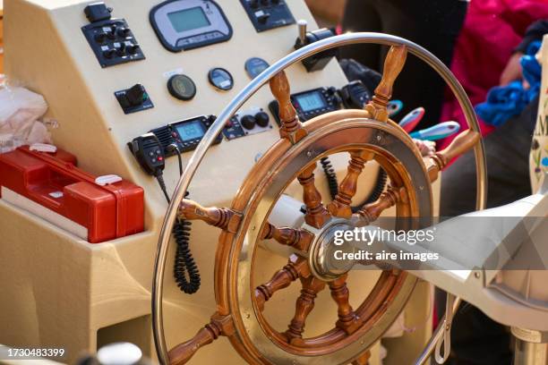 close-up of a ship's helm inside an empty captain's cabin with a control panel on the side, side view - rudder stock pictures, royalty-free photos & images