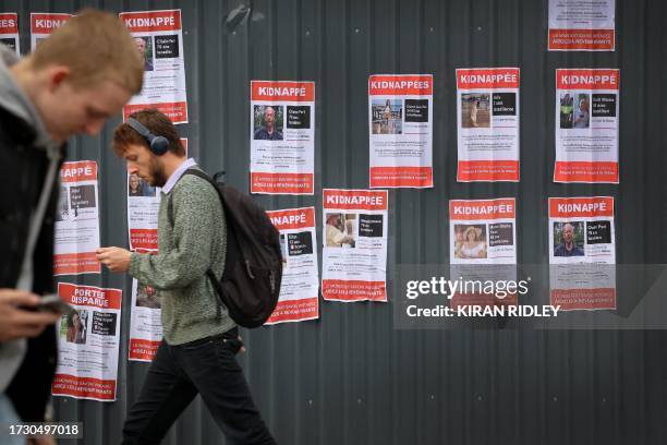 People walk past kidnap and disappearance posters, showing recently kidnapped or missing Israelis, following the Hamas attacks on Israel, in central...