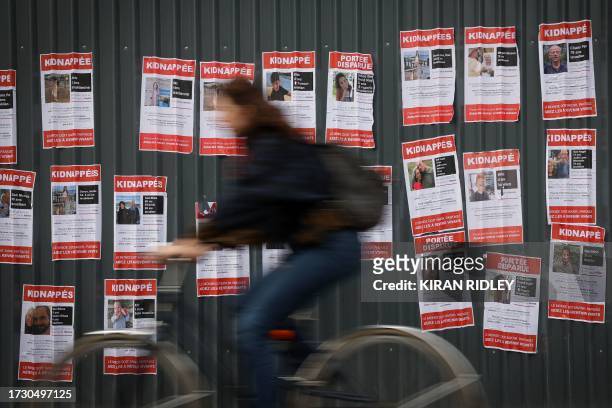 Cyclist rides past kidnap and disappearance posters, showing recently kidnapped or missing Israelis, following the Hamas attacks on Israel, in...