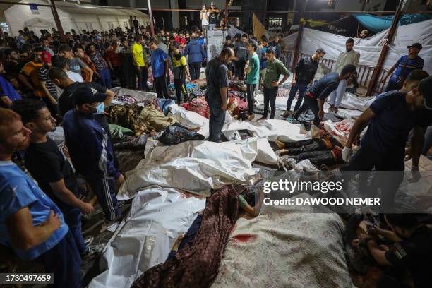 Graphic content / TOPSHOT - People gather around bodies of Palestinians killed after a strike ripped through the Ahli Arab hospital in central Gaza...