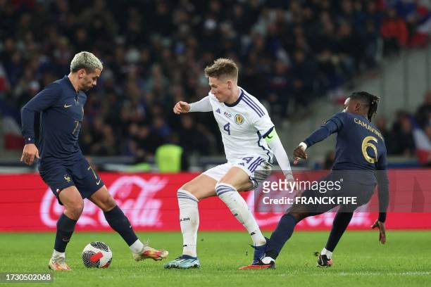 Scotland's midfielder Scott McTominay fights for the ball with France's forward Antoine Griezmann and France's midfielder Eduardo Camavinga during...