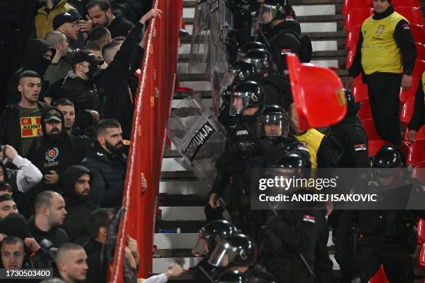Montenegro's supporters clash with security personnel and riot police officers during the UEFA Euro 2024 Group G qualifying football match between...