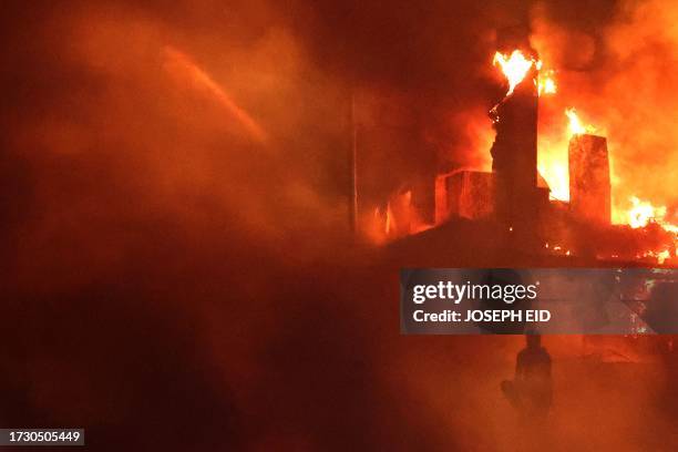 Lebanese protester sits outside the US embassy as a fire rages behind its gates after clashes with Lebanese security forces on October 18 during a...