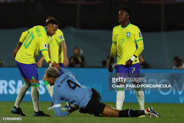 Brazil's forward Neymar helps Uruguay's defender Ronald Araujo to stand up next to Brazil's forward Vinicius Jr during the 2026 FIFA World Cup South...