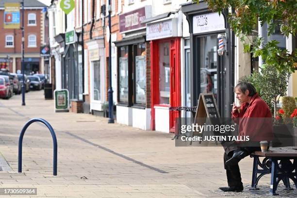 Person has a coffee and cigarette on the High Street in Shefford, central Bedfordshire, north of London, on October 17, 2023. Voters go to the polls...