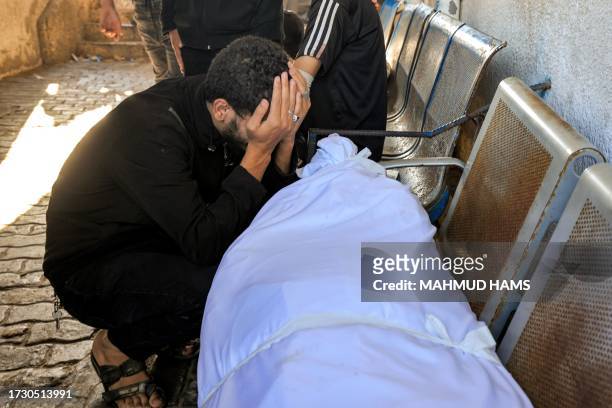 Graphic content / A man reacts by one of the wrapped bodies of victims who died in an overnight strike at the Ahli Arab hospital in Gaza City on...
