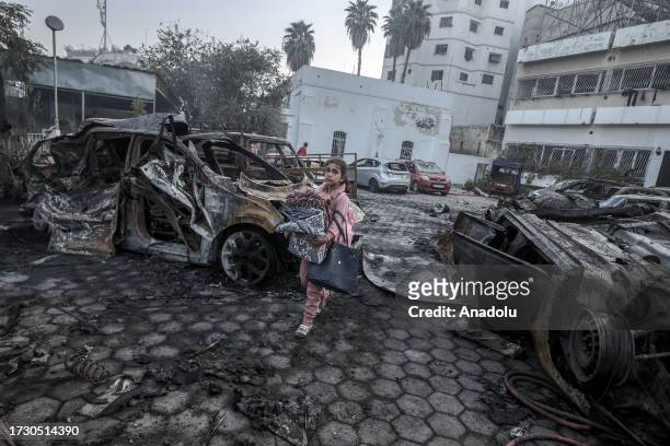 Girl tries to collect usable belongings amid wreckage of vehicles after Al-Ahli Baptist Hospital was hit in Gaza City, Gaza on October 18, 2023. Over...