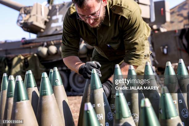 An Israeli army soldier adjusts the tip to a 155mm artillery shell near a self-propelled howitzer deployed at a position near the border with Lebanon...