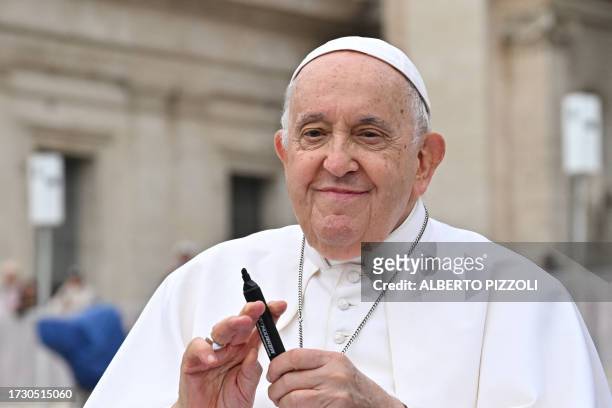 Pope Francis holds a marker after he signed a banner at the end of the weekly general audience at St Peter's square in The Vatican on October 18,...