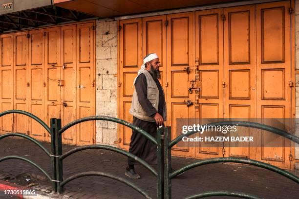 Man walks past closed shops along a street in the city of Hebron in the occupied West Bank on October 18 during a general strike called in response...