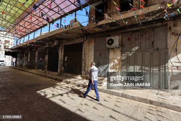 Palestinian man walks past shuttered shops during a general strike in Nablus in the occupied West Bank, on October 18 a day after a rocket hit a Gaza...