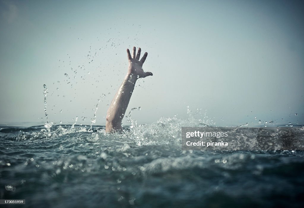 Hand emerges splashing water from below