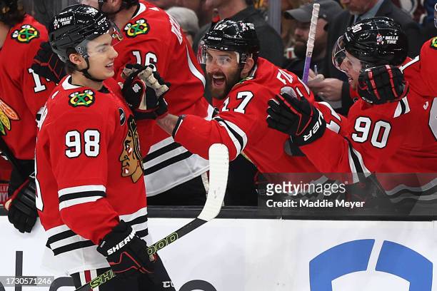 Connor Bedard of the Chicago Blackhawks celebrates with Nick Foligno and Tyler Johnson after scoring his first NHL goal during the first period of...