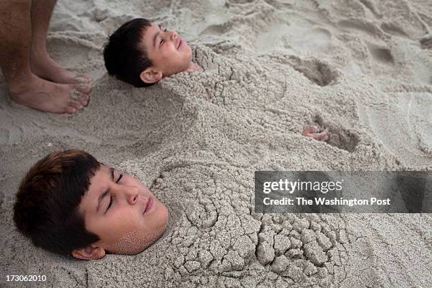 Seaside Heights, NJ Cousins Dylan Sibaja and Aiden Herea from Hilsboro, NJ, bury themselves in sand at Seaside Heights, NJ on June 30, 2013. People...