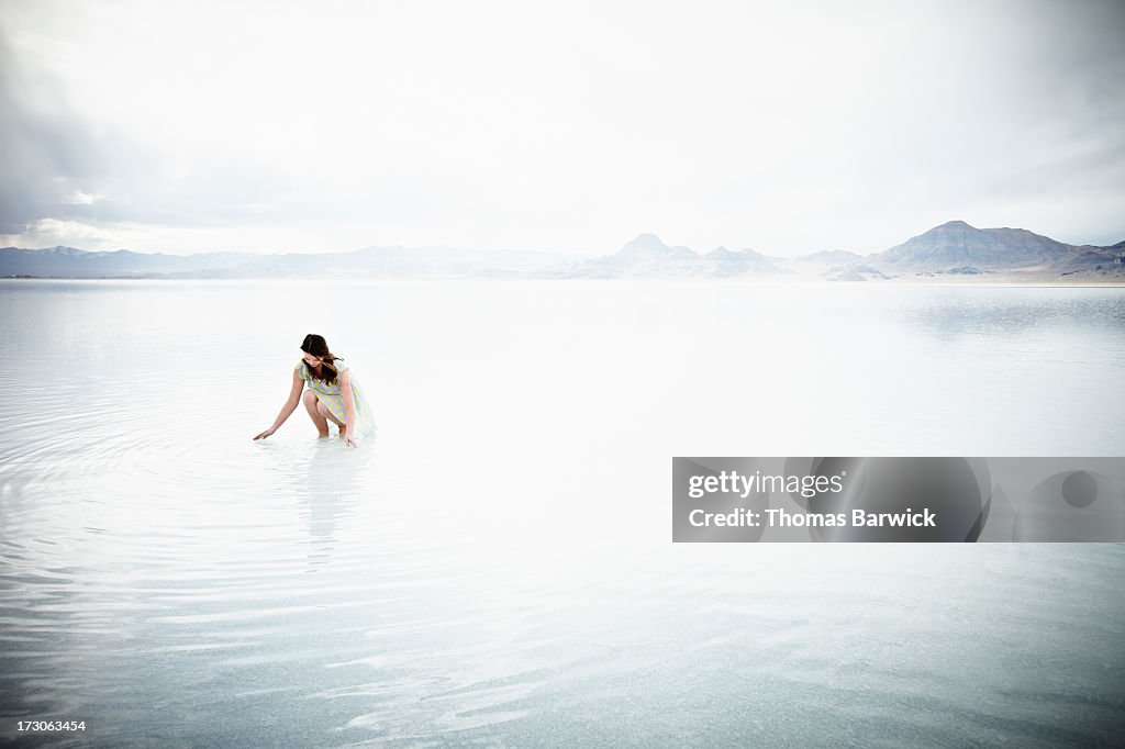 Woman kneeling with hands touching water