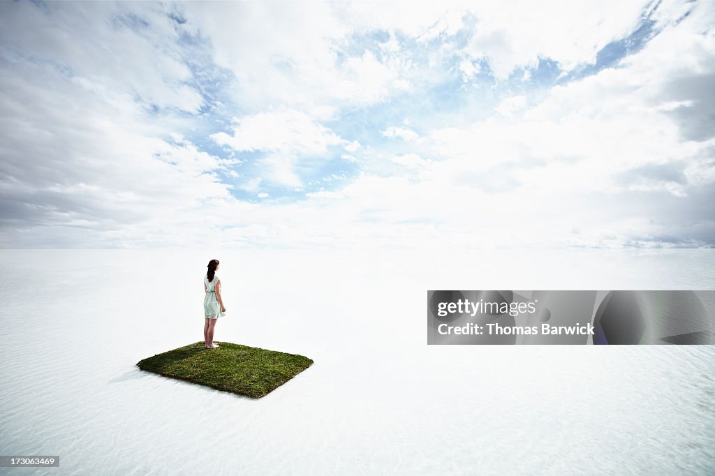 Woman on small grass island in large body of water