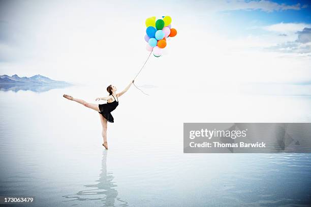 ballerina on tip toe in water holding balloons - harmony fotografías e imágenes de stock