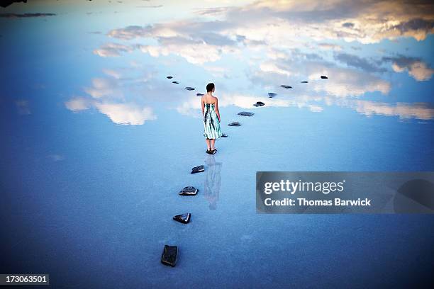 woman standing at fork in stone pathway in lake - dreams photos et images de collection