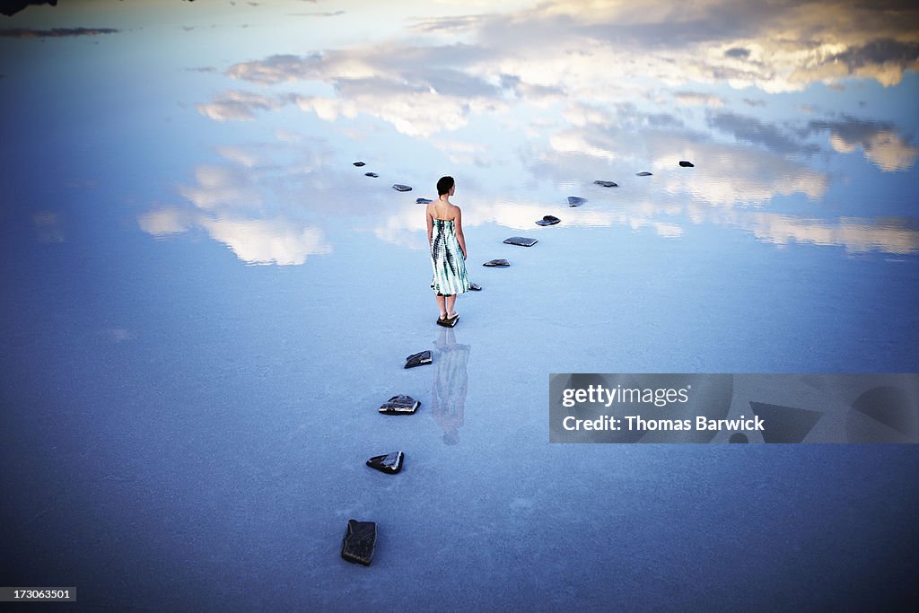 Woman standing at fork in stone pathway in lake