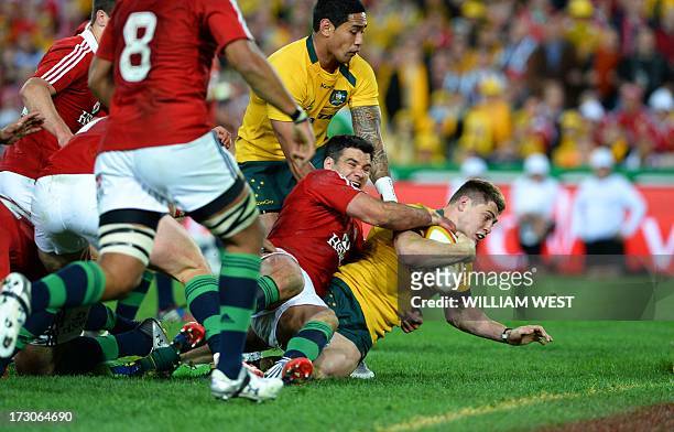 Australian Wallabies flyhalf James O'Connor dives through the tackle of British and Irish Lions halfback Mike Phillips to score a try as teammate Joe...