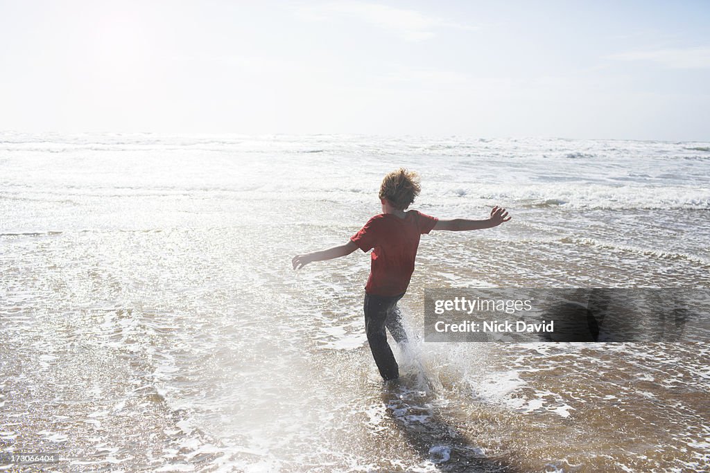 Boy kicking water at the seaside