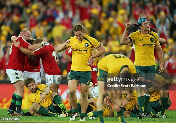 Wallabies captain James Horwill and Michael Hooper look dejected as the Lions celebrate victory at the final whistle during the International Test...