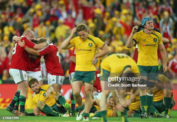 Wallabies captain James Horwill and Michael Hooper look dejected as the Lions celebrate victory at the final whistle during the International Test...