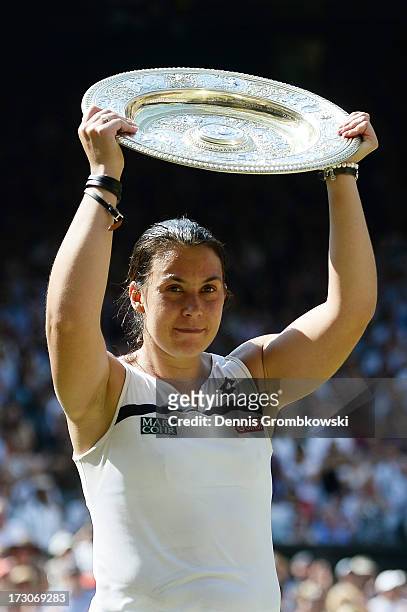 Marion Bartoli of France poses with the Venus Rosewater Dish trophy after her victory in the Ladies' Singles final match against Sabine Lisicki of...